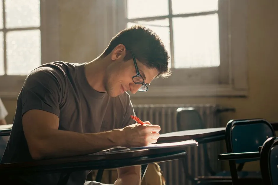 Student writing out practice problems at a desk during a focused study session