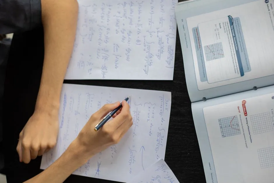 Close-up of a person writing out a math problem by hand on paper